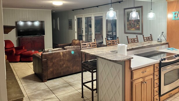 A modern kitchen with a central island, bar stools, a built-in oven, and pendant lighting. - Right at Home-Midland Home away from Home with Billiards (Midland)