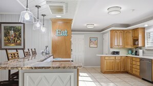 A kitchen with a marble island, wooden cabinets, pendant lights, and a door with the word 'Eat' on it. - Right at Home-Midland Home away from Home with Billiards (Midland)