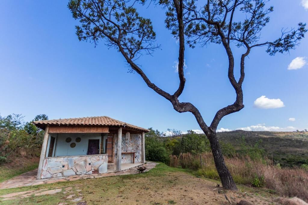 Un edificio de piedra rústico con techo de tejas, rodeado de césped y un árbol destacado.