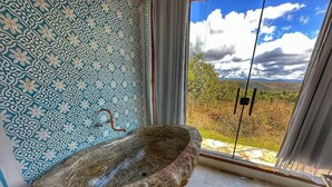Une salle de bain avec un lavabo en pierre, des murs décorés de motifs et une vue sur l’extérieur.