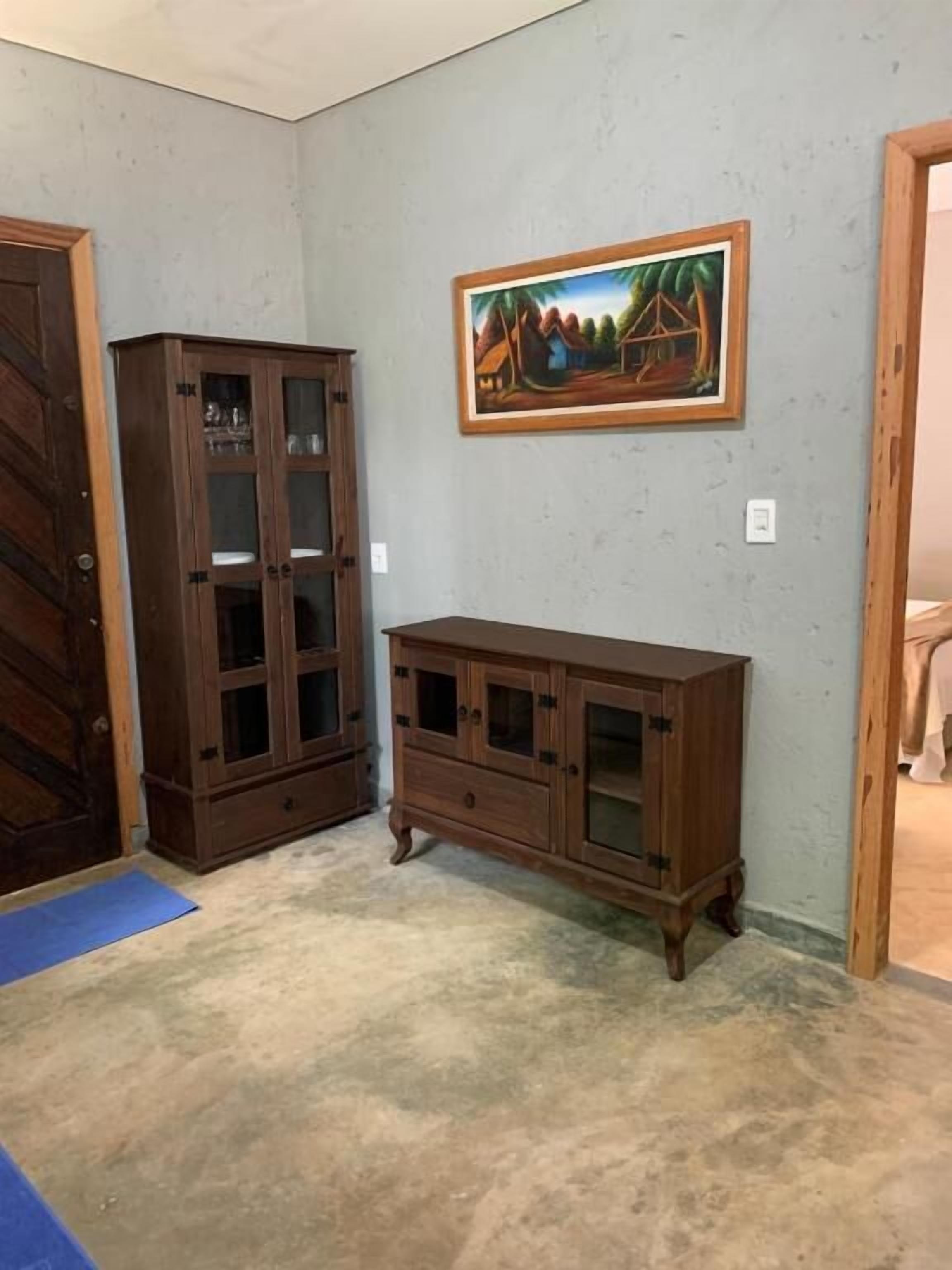 Una habitación con un armario de madera, un cuadro en la pared y un tapete azul en el suelo.