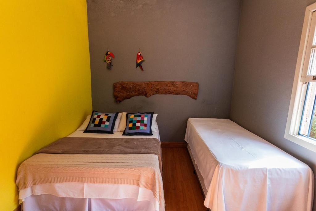 Una habitación pequeña con dos camas, cabecero de madera y una ventana.