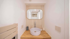 Un baño con un lavabo redondo, un espejo y un mueble de tocador de madera.