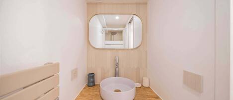 A bathroom with a round sink, a mirror, and a wooden vanity.