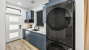 Een kleine keuken met een spoelbak, kastjes en een groot apparaat.