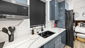 Een moderne keuken met een magnetron, spoelbak en koelkast.
