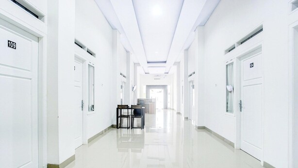Un long couloir étroit, avec des portes blanches, chacune portant un numéro.