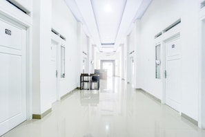 Un long couloir étroit, avec des portes blanches, chacune portant un numéro.