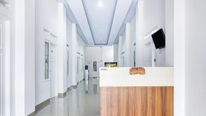 A hotel reception area with a wooden reception desk, a flat-screen TV, and a reception sign. - Stylish Double Suite Escape with Parking Access (Bandar Lampung)
