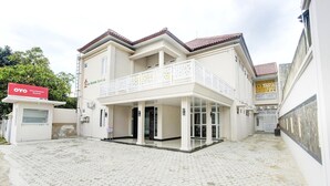 A two-story building with a balcony, a signboard, and a paved courtyard. - Stylish Double Suite Escape with Parking Access (Bandar Lampung)