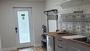 Et køkken med trægulv, opvaskemaskine, vask og en dør med frostet glas.