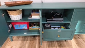 A teal-colored storage unit with shelves containing books, a PlayStation 4, and a red storage box.