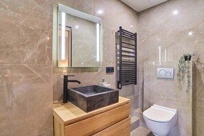 Une salle de bain avec un lavabo en marbre, un miroir, un porte-serviettes et des toilettes.