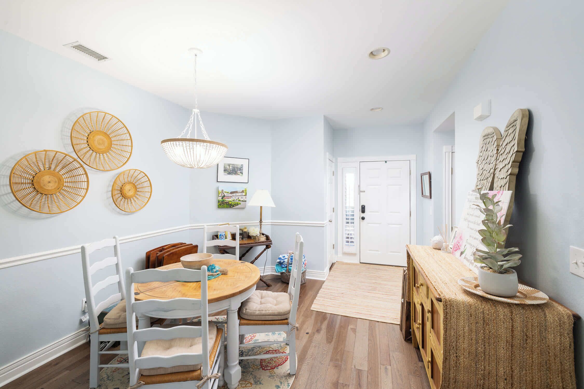 A dining area with a round table, white chairs, and a wooden bench.