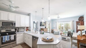Une cuisine moderne avec des meubles blancs, des appareils en acier inoxydable et un îlot central.