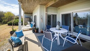 Une terrasse extérieure avec une table et des chaises, un banc avec des coussins et une plante en pot.