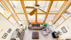A spacious living room with a ceiling fan, large windows, and a view of the outdoors. - Black Butte Ranch Retreat • 3BR+loft & AC • Walk to Glaze Meadow (Sisters)