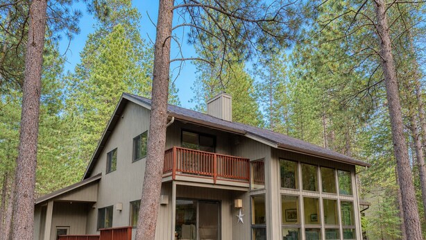 A two-story cabin with a balcony, large windows, and a deck. - Black Butte Ranch Retreat • 3BR+loft & AC • Walk to Glaze Meadow (Sisters)
