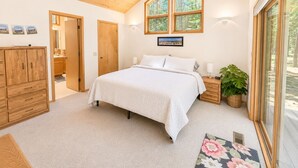 A bedroom with a large bed, wooden wardrobe, and a window with a view of trees. - Black Butte Ranch Retreat • 3BR+loft & AC • Walk to Glaze Meadow (Sisters)