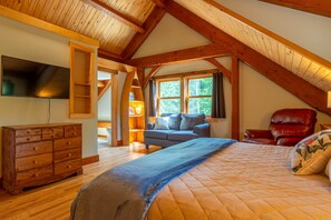 A bedroom with a wooden ceiling, a bed, a dresser, a TV, and a window.