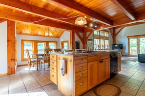 A spacious kitchen with wooden cabinetry, a large island, and a dining area with chairs.