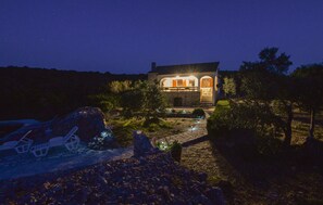 A stone house with a stone pathway leading to the entrance, surrounded by trees and a rocky landscape. - Beautiful home in Tkon with WiFi (Tkon)