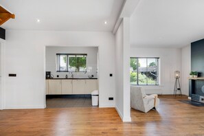 Una cocina moderna con armarios blancos, suelo de madera y vistas al exterior a través de amplios ventanales.