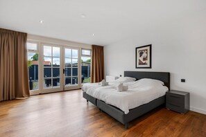 A bedroom with a large bed, a nightstand, a framed picture, and a sliding glass door leading to an outdoor area. - Spacious holiday home in the center of Langweer (Langweer)