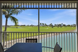 Ein Zimmer mit Blick auf einen Golfplatz, eine Palme und einen Tisch.