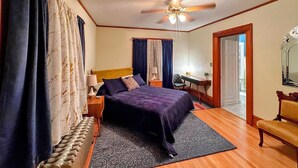 Une chambre d’hôtel équipée d’un lit, d’un bureau, d’une chaise, d’un ventilateur de plafond et d’un grand miroir.