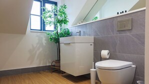 Ein modernes Badezimmer mit Toilette, Bidet und einem Fenster mit Pflanze.