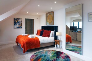 A modern bedroom with a bed, a mirror, a desk, and a colorful rug. - Luxury King Room - Penarth (Vale of Glamorgan)