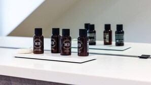 Ein Badezimmer-Waschtisch mit mehreren Flaschen Duschgel und Shampoo, einer Seifenschale und einem Spiegel.