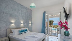 A bedroom with a bed, bedside table, and a view of the outside. - Villa Zeta (Paros)