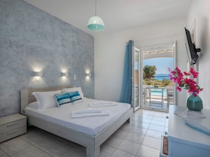 A bedroom with a bed, bedside table, and a view of the outside. - Villa Zeta (Paros)