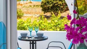 A balcony with a table and chairs, a view of the sea, and a vase of flowers. - Villa Zeta (Paros)