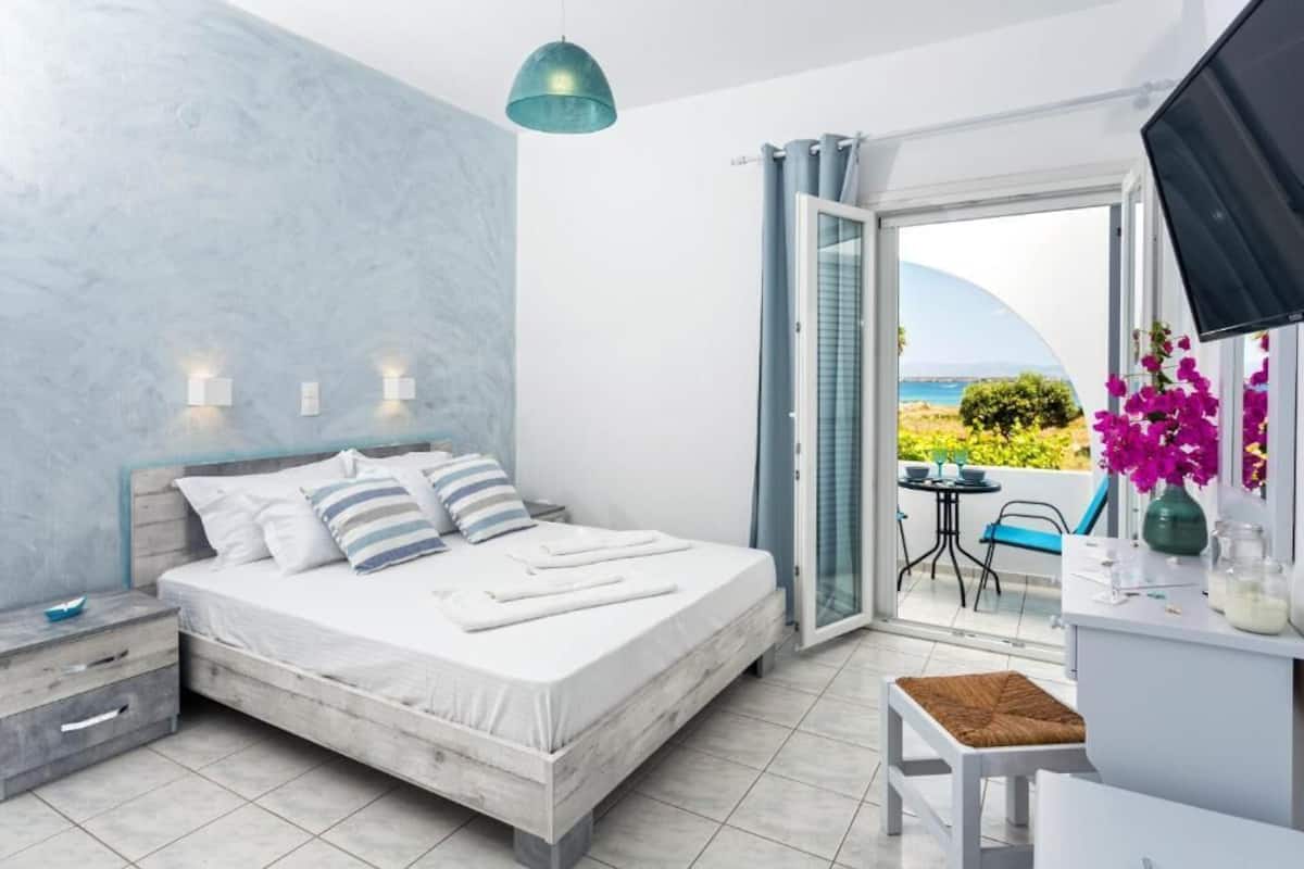 Une chambre à coucher comprenant un lit, des tables de chevet, un bureau, une chaise et une vue sur l’extérieur.