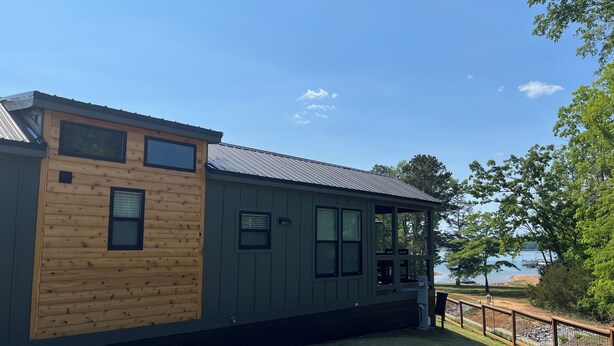 A cabin-style building with a wooden exterior, large windows, and a view of the water. - 2 Bedroom Lake Front Tiny Home in Anderson, beside Legendary Green Pond Landing (Anderson)