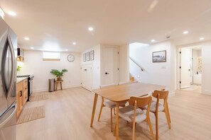 A modern kitchen with a dining area, wooden cabinets, a refrigerator, and a clock on the wall. - New & Modern- 2 Full Kitchens, Sauna, Sleeps 10 (Salt Lake City)