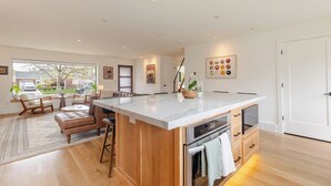 Een moderne keuken met een groot kookeiland, houten kastjes en uitzicht naar buiten.