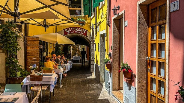 A narrow street with outdoor seating, a restaurant named 'Ristorante Bella Venezia,' and buildings with numbered doors. - Casa Cavour Garda (Garda)