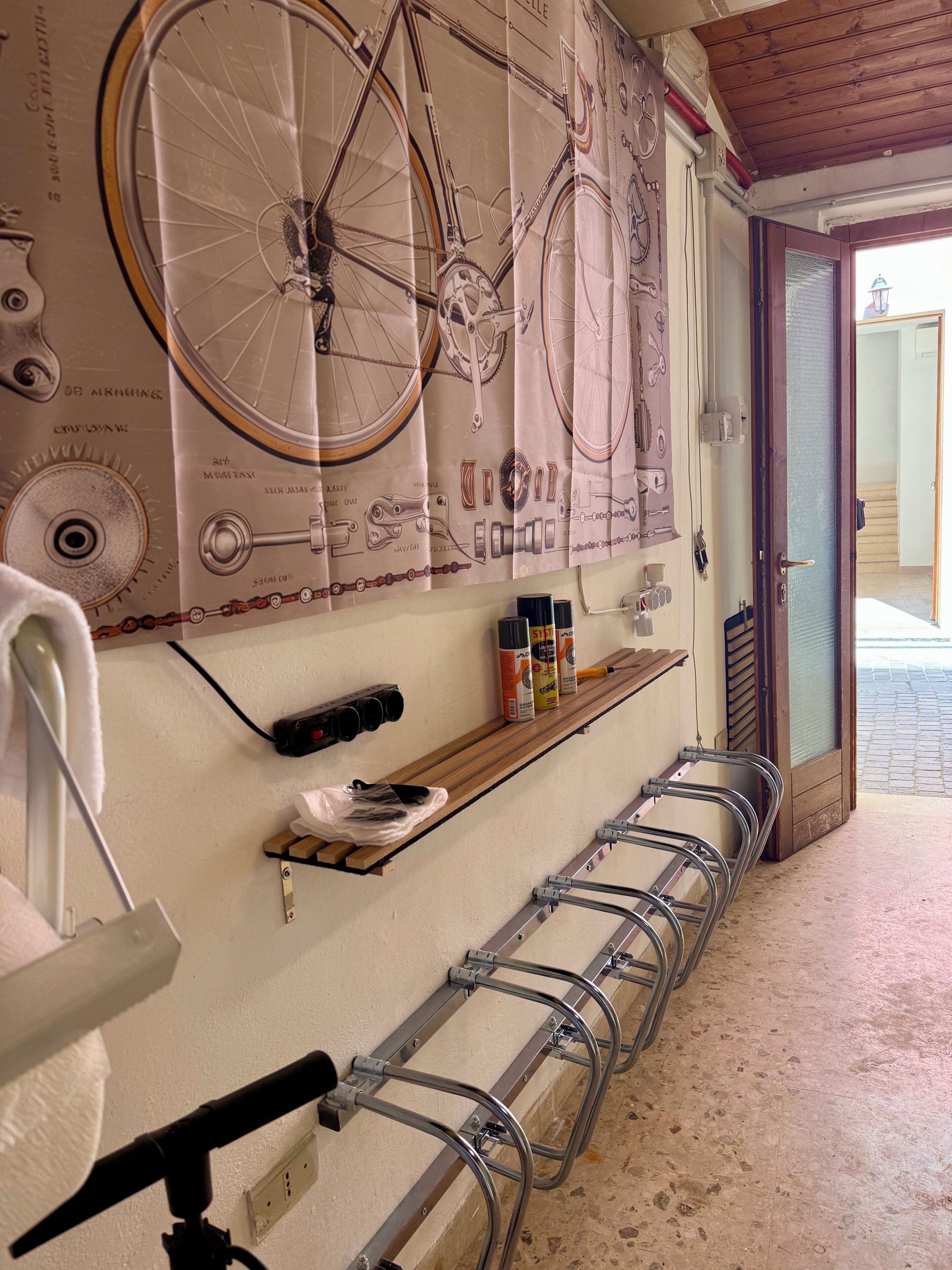 Un baño con un detalle decorativo de bicicletas en la pared, un perchero, un estante con artículos de tocador y un soporte metálico para bicicletas.