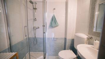 Un baño con ducha de vidrio, inodoro y lavamanos.