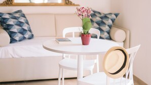 A room with a round white table, a potted plant, a book, and a hat on a chair. - Casa Cavour Garda (Garda)