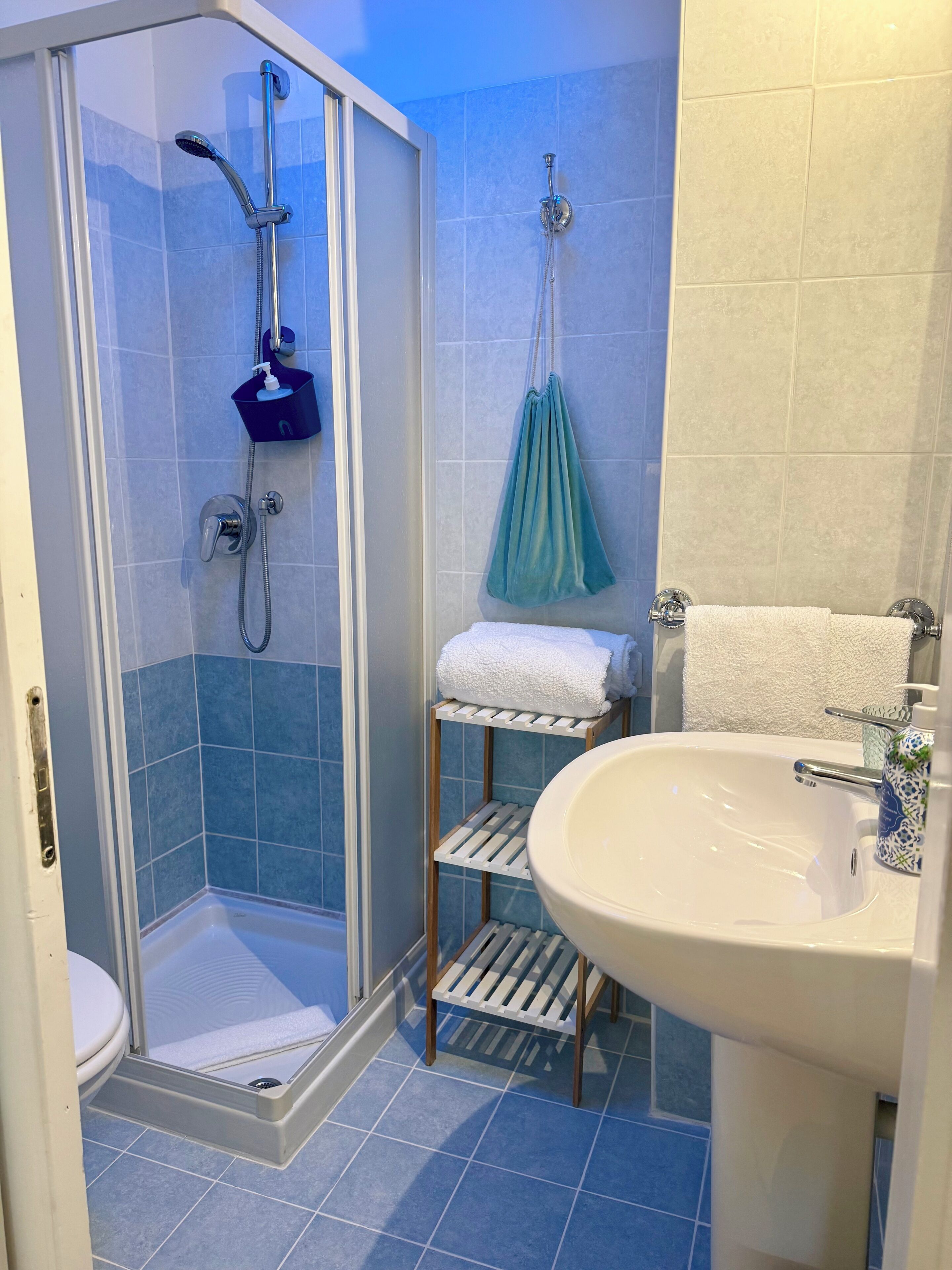 A bathroom with a shower, toilet, sink, and towel rack.