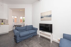 A modern living room with a sofa, a TV, and a dining area with a table and chairs. - HOUZE Spacious 9 bedroom flat in Central Lisbon (Lisboa)