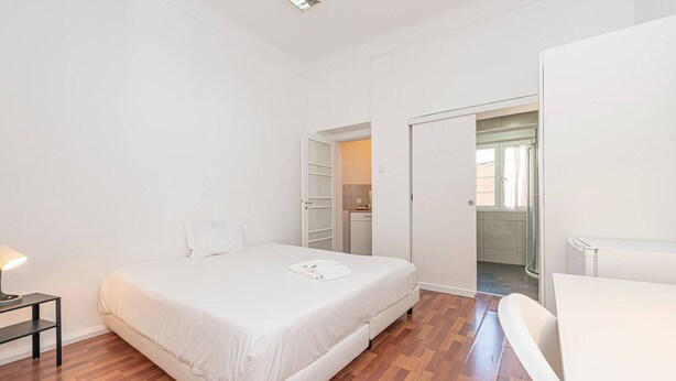 Ein Schlafzimmer mit Bett, Nachttisch und einem Badezimmer mit Dusche und Toilette.