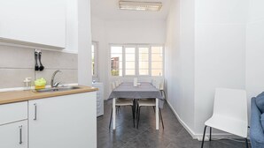 Eine moderne Küche mit weißen Schränken, einer Holzarbeitsplatte und einem Essbereich mit Tisch und Stühlen.