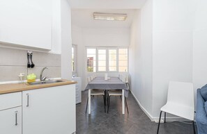 Una cuina moderna amb armaris blancs, tauleig de fusta i zona de menjador amb taula i cadires.