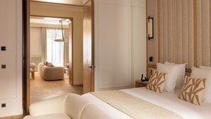 Ett hotellrum med en stor säng, en sittgrupp med en soffa och utsikt in i ett annat rum.